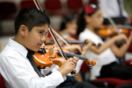 Young boy playing violin with others